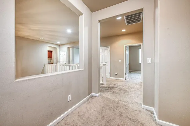 a view of a hallway with wooden floor and a bathroom