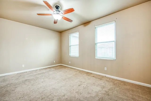 an empty room with windows and fan