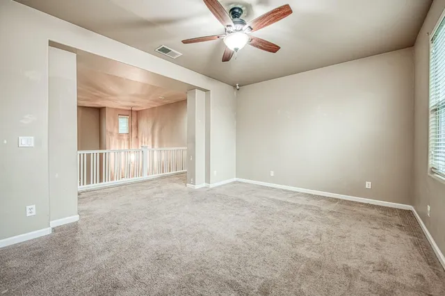 a view of an empty room and chandelier fan