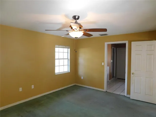 an empty room with a ceiling fan and a window