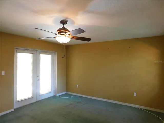 an empty room with windows and fan
