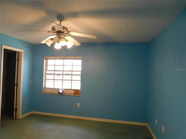 an empty room with windows and fan