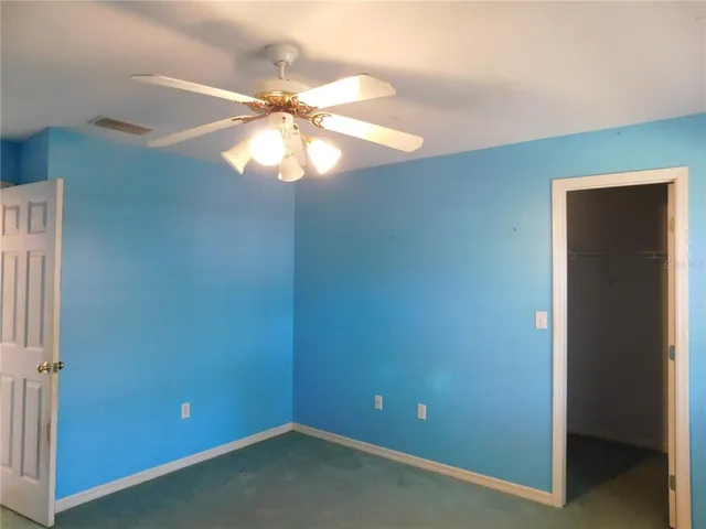 an empty room with a window and a ceiling fan