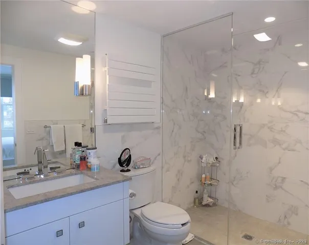 a bathroom with a double vanity sink toilet mirror and shower