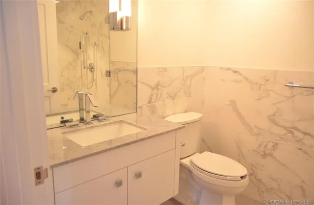 a bathroom with a granite countertop sink a toilet and a mirror