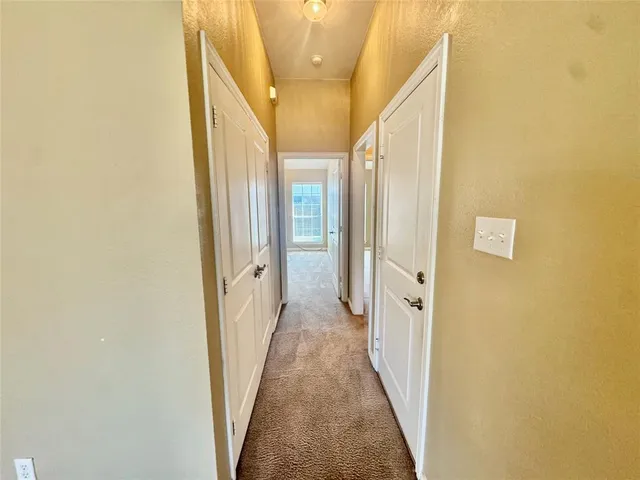 a view of a hallway with white walls and wooden door