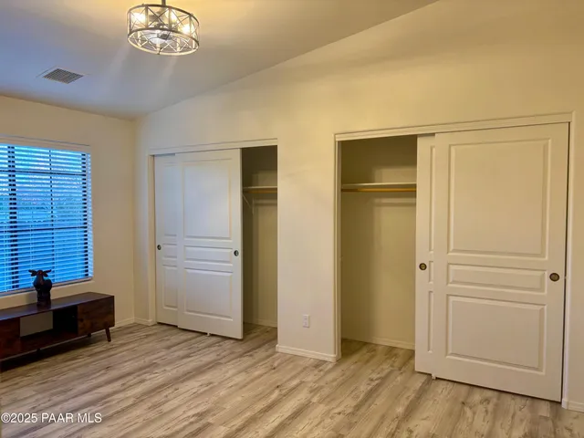 an empty room with wooden floor closet and windows