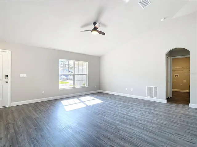 an empty room with wooden floor cabinet and windows