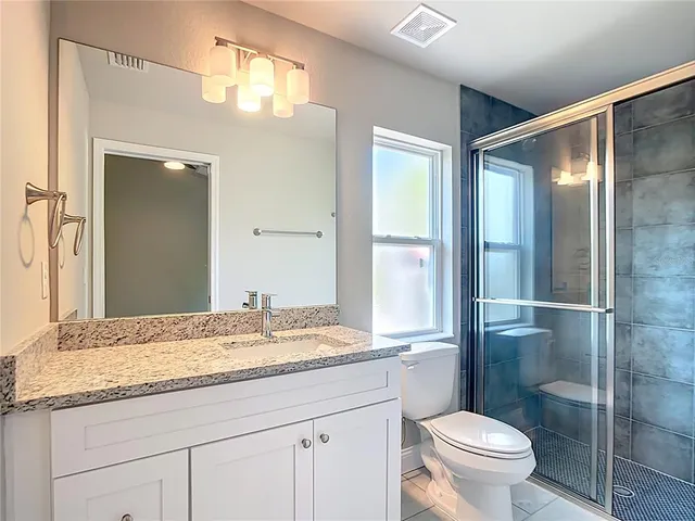 a bathroom with a granite countertop sink toilet and shower