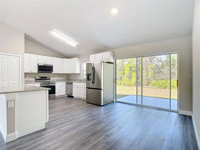 a kitchen with kitchen island wooden floors white appliances and white cabinets