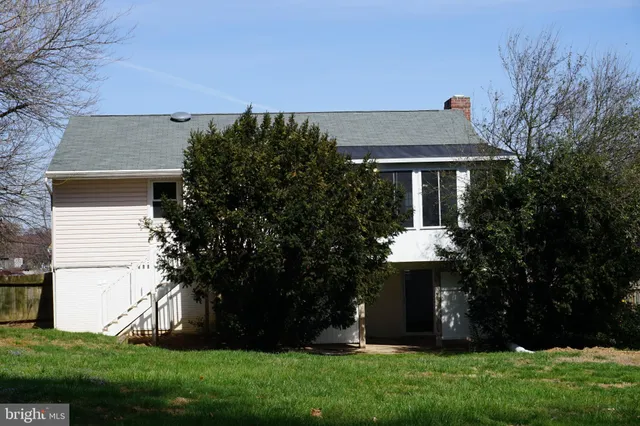a front view of a house with a garden and trees