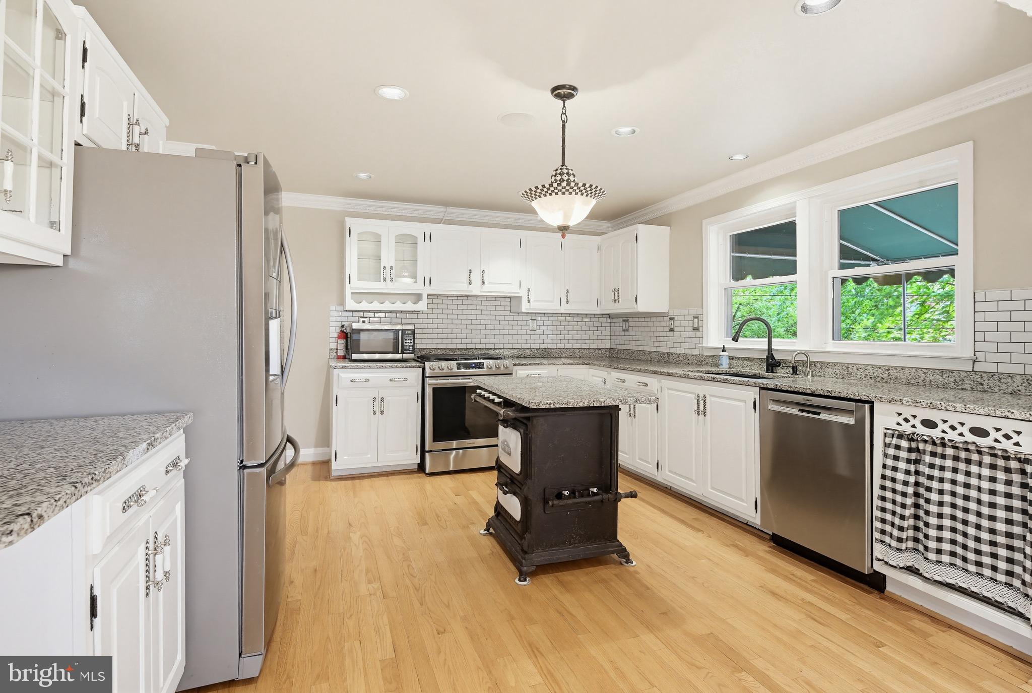 8111 Barksdale Road Baltimore, MD 21286 - Photo 10 of 39 a kitchen with kitchen island granite countertop wooden floors and white cabinets