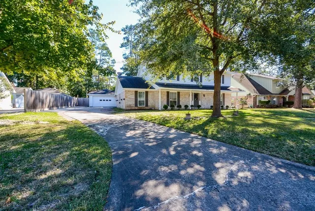 a view of a house with a yard and a large tree