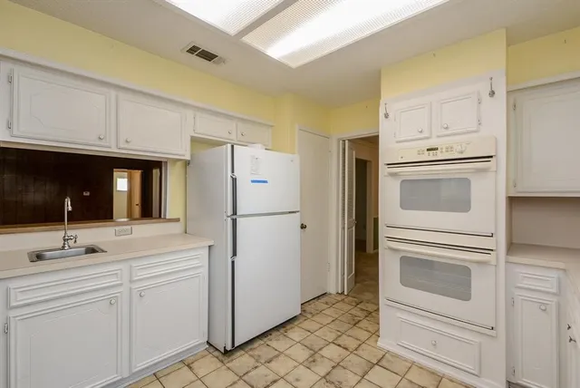 a kitchen with white cabinets and white appliances