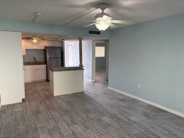 a view of a kitchen with a dishwasher a kitchen island wooden floor and ceiling fan