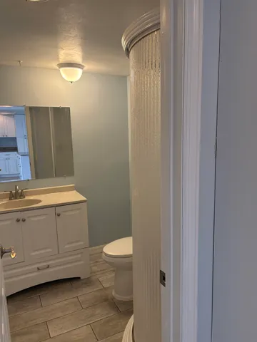 a bathroom with a granite countertop toilet and a sink