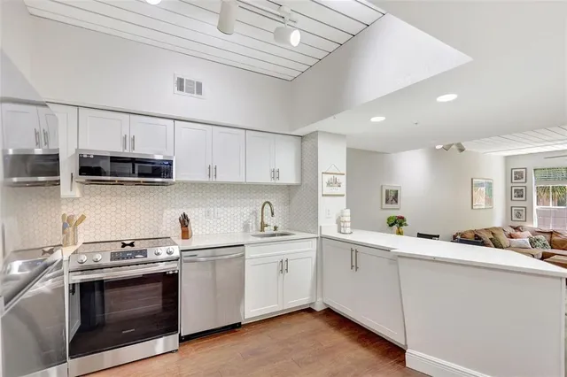 a kitchen with stainless steel appliances a sink a stove a microwave and cabinets