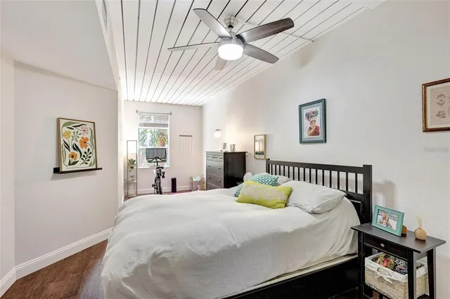 a bedroom with a bed a dresser and paintings on the wall