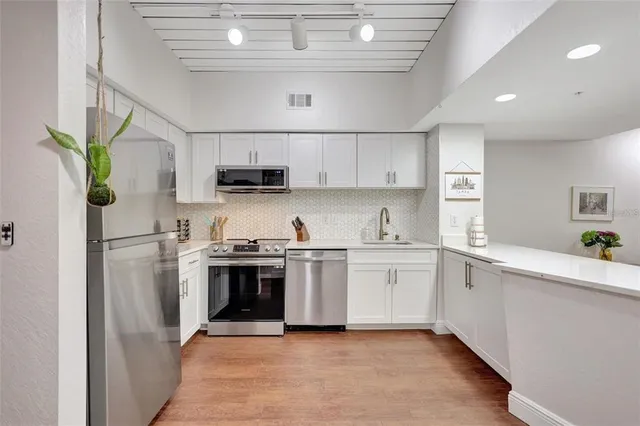 a kitchen with stainless steel appliances granite countertop a sink a stove a refrigerator and a refrigerator