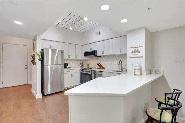 a kitchen with a sink a refrigerator and white cabinets