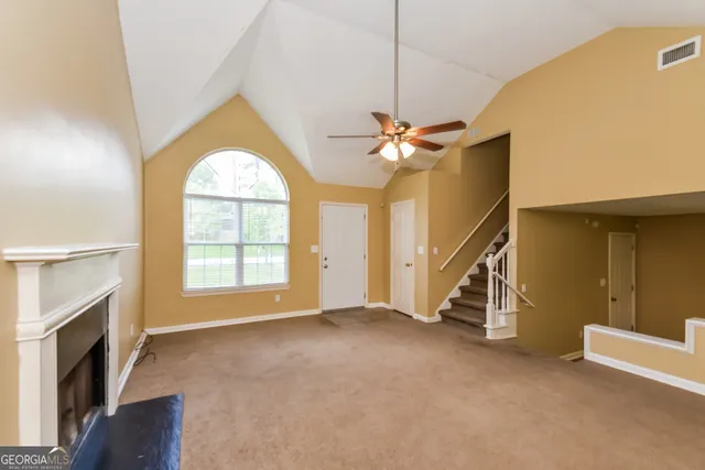 an empty room with windows fireplace and a chandelier