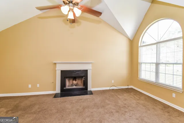 an empty room with windows and fireplace