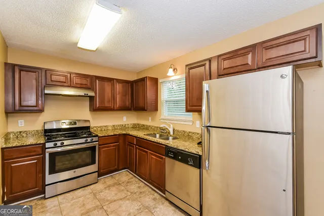 a kitchen with stainless steel appliances a refrigerator sink and stove