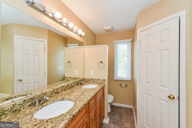 a bathroom with a granite countertop double vanity sink a mirror and a shower
