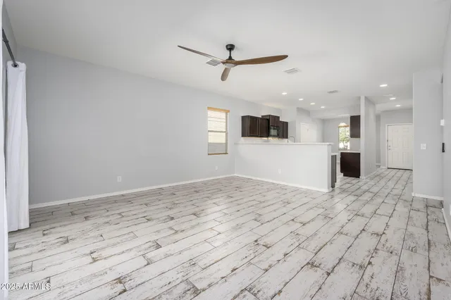 a view of empty room with wooden floor and a ceiling fan