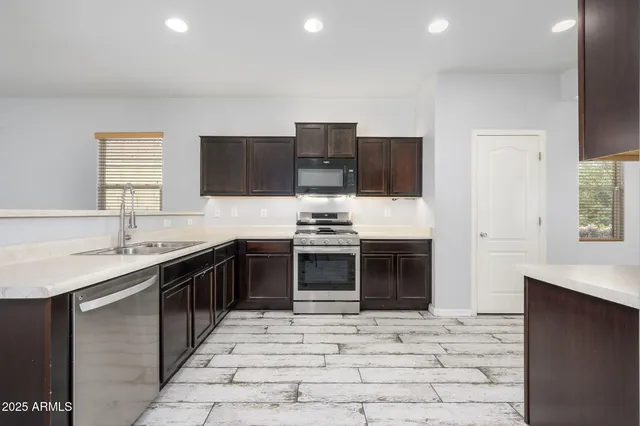 a kitchen with stainless steel appliances granite countertop a stove top oven a sink and a refrigerator