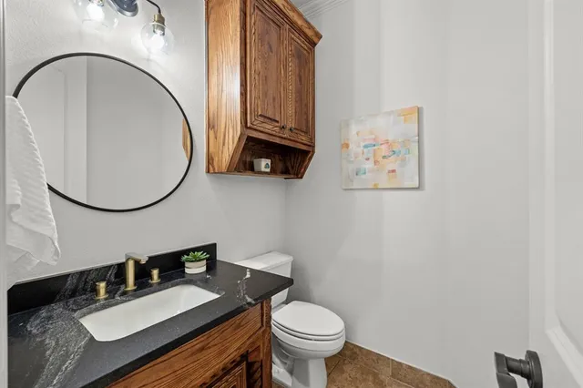 a bathroom with a granite countertop toilet a sink and a mirror
