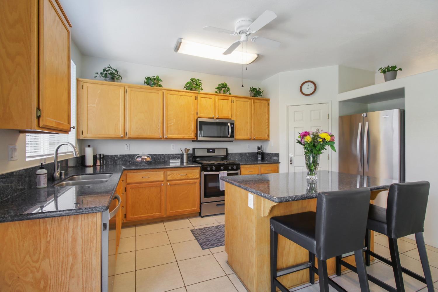 11568 Pyrites Court Gold River, CA 95670 - Photo 15 of 60 a kitchen with stainless steel appliances granite countertop a refrigerator a stove top oven a sink a dining table and chairs with wooden floor