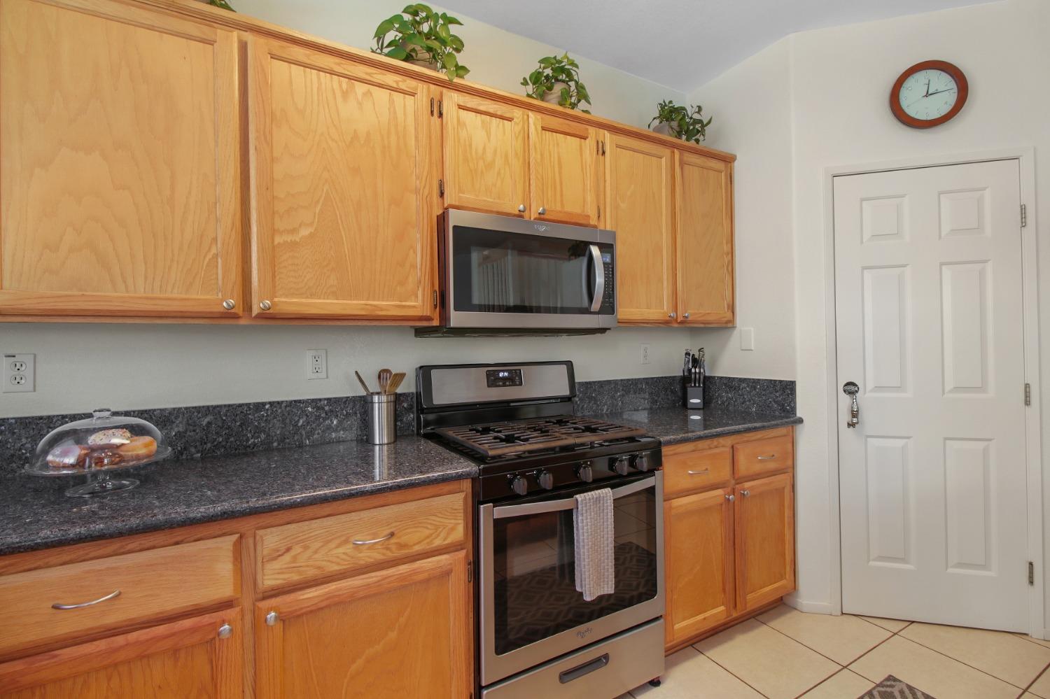 11568 Pyrites Court Gold River, CA 95670 - Photo 17 of 60 a kitchen with granite countertop a stove a sink a microwave and cabinets