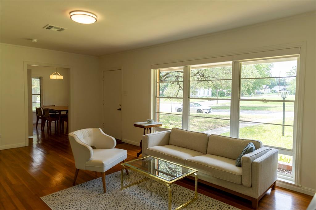 3228 Colcord Avenue Waco, TX 76707 - Photo 22 of 29 Living area featuring expansive windows, wood-finish flooring, a contemporary ceiling light fixture, and an open entryway to an adjacent room