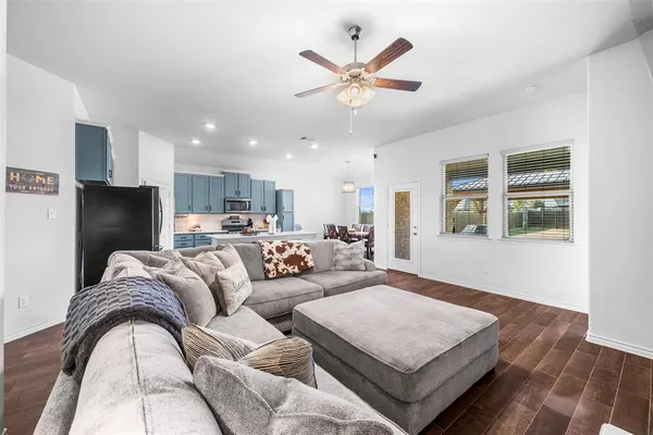a living room with couches and kitchen view with wooden floor