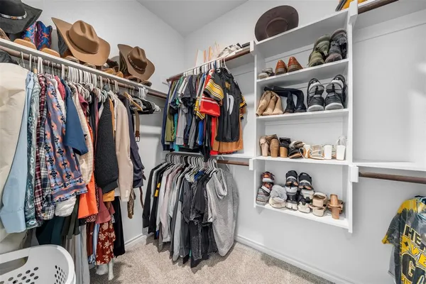 a view of walk in closet with clothes and shoes