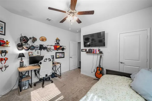 a bedroom with furniture a flat screen tv and a chandelier fan
