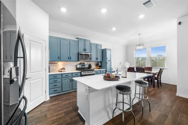 a kitchen with stainless steel appliances a dining table chairs stove refrigerator and cabinets