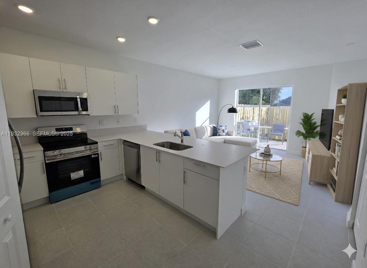 12136 Southwest 268th Street Homestead, FL 33032 - Photo 4 of 11 a kitchen with stainless steel appliances a sink a stove a refrigerator cabinets and a window