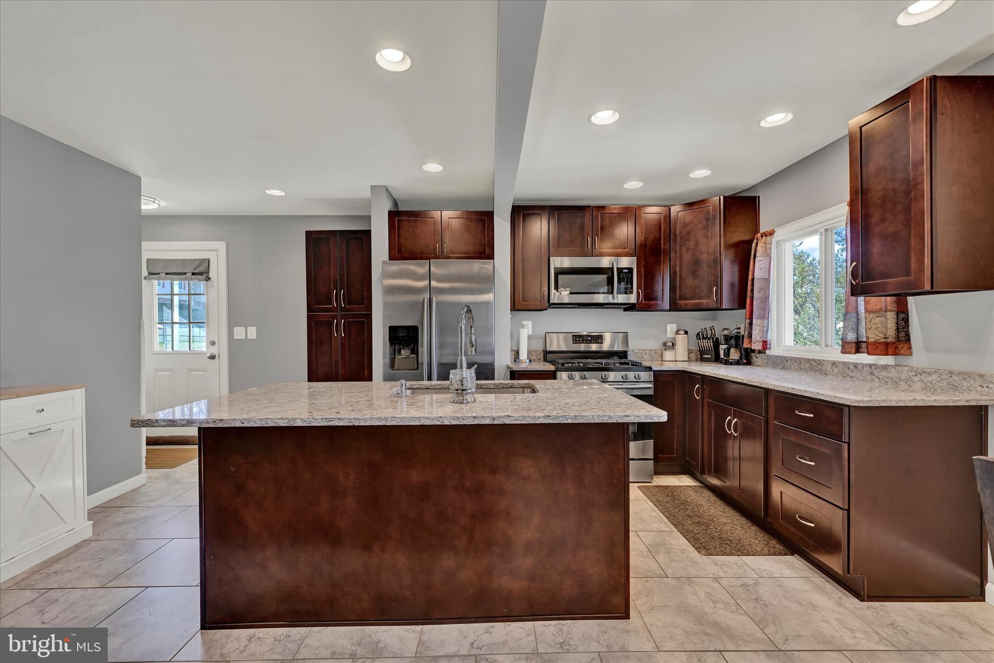 9630 10th Avenue Baltimore, MD 21234 - Photo 10 of 35 a kitchen with kitchen island granite countertop a sink counter top space appliances and cabinets