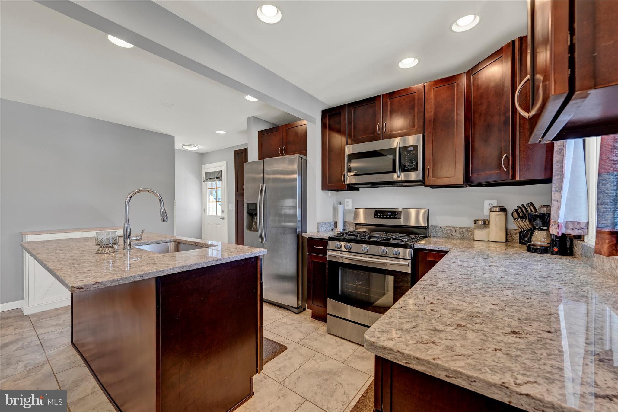 9630 10th Avenue Baltimore, MD 21234 - Photo 13 of 35 a kitchen with stainless steel appliances granite countertop a sink stove and refrigerator