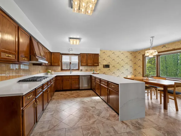 a large kitchen with stainless steel appliances granite countertop a stove top oven a sink dishwasher a dining table and chairs with wooden floor
