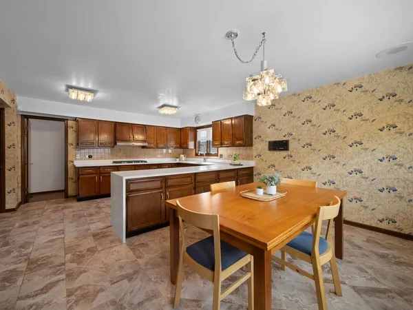 a kitchen with stainless steel appliances kitchen island granite countertop a sink a stove a dining table and chairs