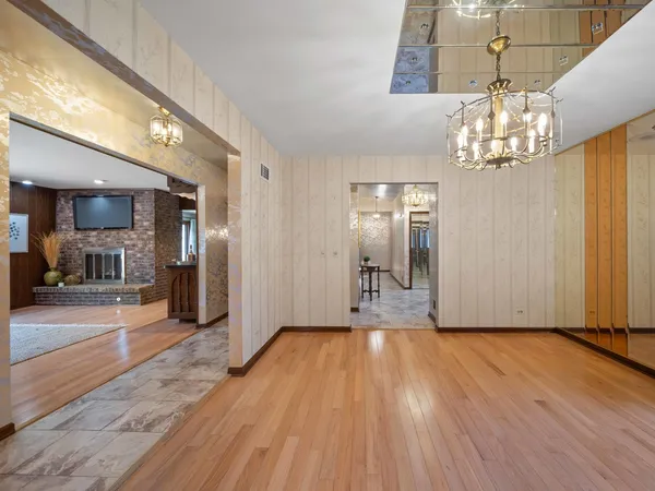 a view of a hallway with wooden floor and a chandelier