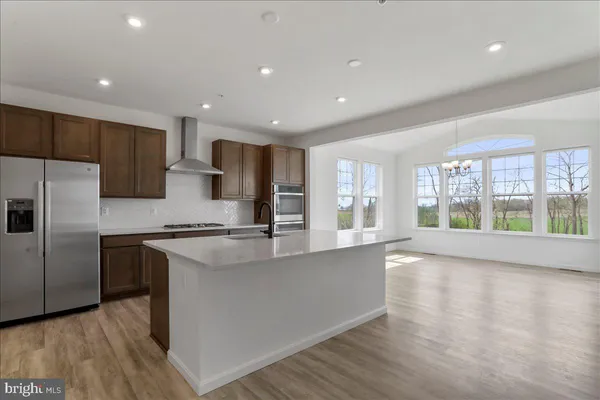 a large kitchen with stainless steel appliances granite countertop a refrigerator a sink a stove and a wooden floors