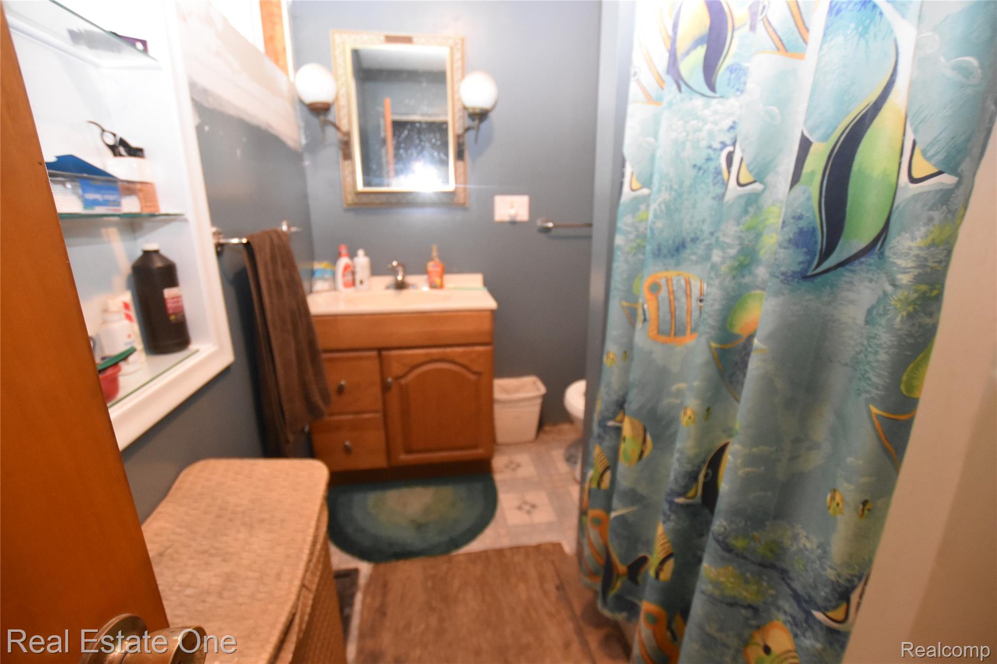 3482 West Maple Road Wixom, MI 48393 - Photo 14 of 17 Wood-finish vanity with a single basin sink and wall-mounted mirror