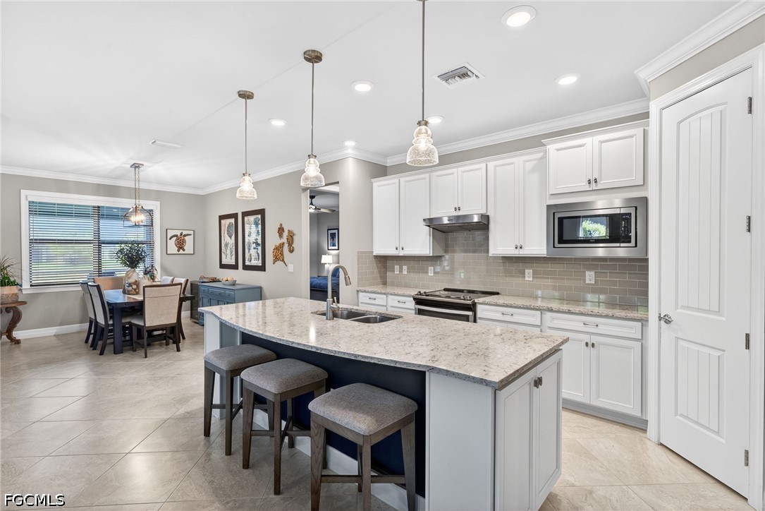 11932 Bourke Place Fort Myers, FL 33913 - Photo 5 of 44 a kitchen with stainless steel appliances granite countertop a stove a sink a oven a dining table and chairs