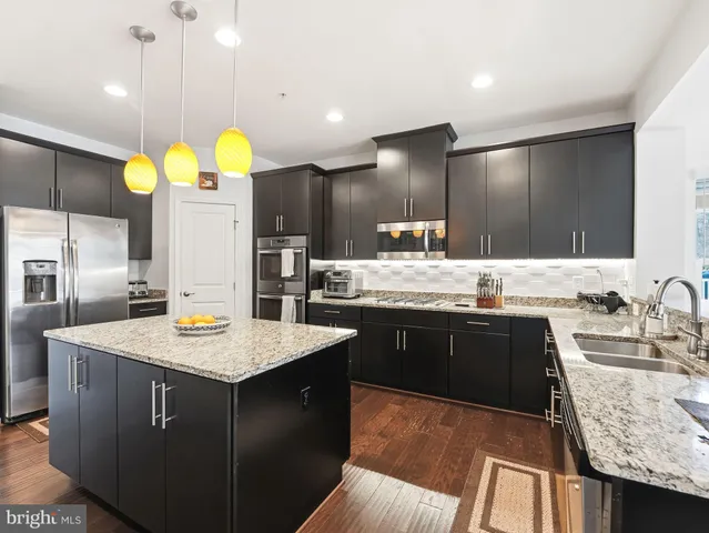 a kitchen with kitchen island granite countertop a sink a counter top space and stainless steel appliances