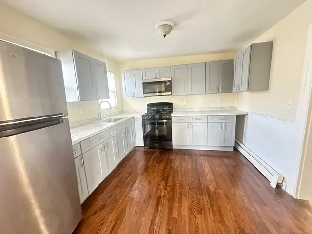 a kitchen with a refrigerator a stove top oven and wooden floor