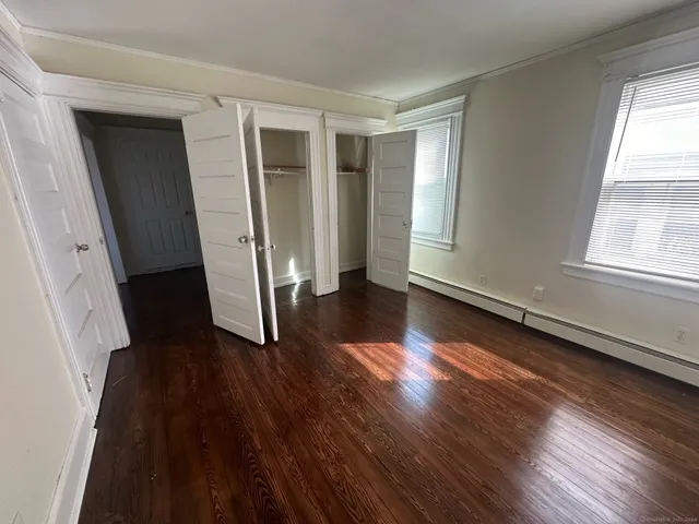 an entryway at an empty room with wooden floor and a window